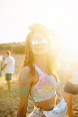 Gökkuşağı renkli tozla kaplı mutlu kadın Holi renk festivalini kutluyor. Genç bir kadın açık havada renkli tozla eğleniyor. Plaj partisi. Geleneksel Hint tatili.