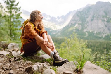 Yürüyüş parkurunda, açık bir dağın tepesinde, yürüyüş botlarıyla kadın bacaklarının yakın çekimi. Seyahat, tatil konsepti.