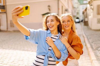 Bir turistin kadını akıllı telefon kamerasıyla sokaklarda dolaşıyor ve selfie çekiyor. Yaşam tarzı, seyahat, turizm, aktif yaşam.