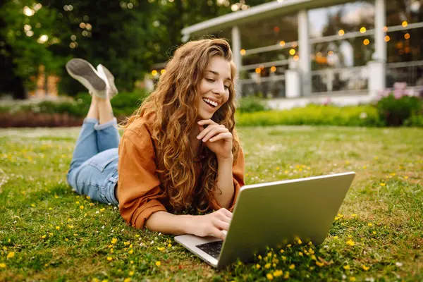 Vrolijke Vrouw Met Krullend Haar Met Een Laptop Buiten Online Stockfoto