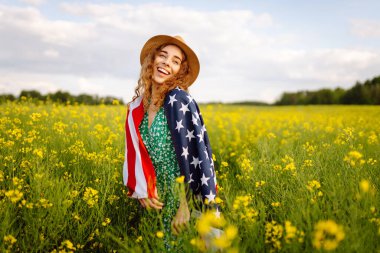 Amerikan bayrağı taşıyan kadın vatansever sahada günbatımının tadını çıkarıyor. 4 Temmuz. Bağımsızlık Günü. 