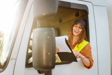 Kamyon şoförü kadın. Kamyon kabininde elinde dosya var. Aracın içinde. İnsanlar ve ulaşım kavramı.