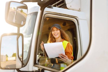 Kamyon şoförü kadın. Kamyon kabininde elinde dosya var. Aracın içinde. İnsanlar ve ulaşım kavramı.