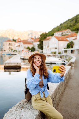 Genç bayan turist akıllı telefondan fotoğraf çekerek yeni şehri keşfediyor. Selfie zamanı. Yaşam tarzı, macera, doğa, aktif yaşam.