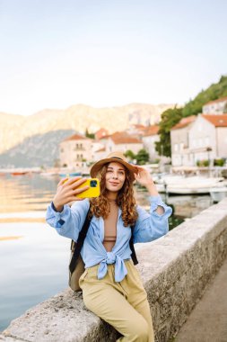 Genç bayan turist akıllı telefondan fotoğraf çekerek yeni şehri keşfediyor. Selfie zamanı. Yaşam tarzı, macera, doğa, aktif yaşam.