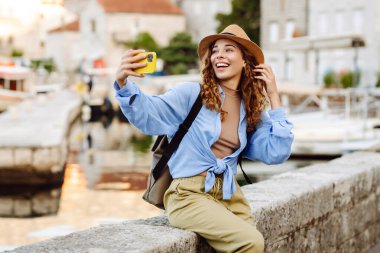 Genç bayan turist akıllı telefondan fotoğraf çekerek yeni şehri keşfediyor. Selfie zamanı. Yaşam tarzı, macera, doğa, aktif yaşam.
