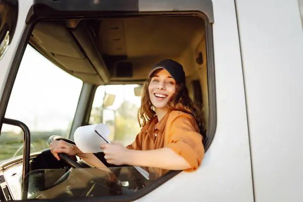 Woman truck driver steering wheel inside lorry cabin with clipboard. Inside of vehicle. People and transportation concept.