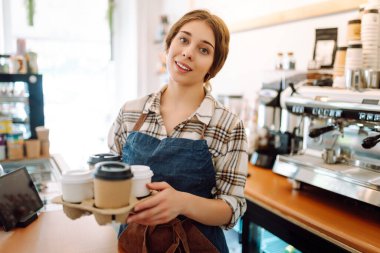 Kahve dükkanındaki müşteriye gülümseyerek kahve servisi yapan güzel bir barista. Paket yemek..