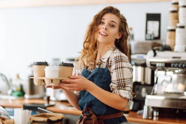 Kahve dükkanındaki müşteriye gülümseyerek kahve servisi yapan güzel bir barista. Paket yemek..