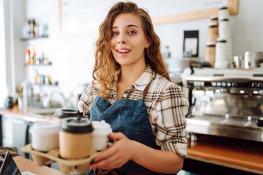 Kahve dükkanındaki müşteriye gülümseyerek kahve servisi yapan güzel bir barista. Paket yemek..