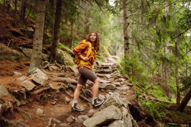 Yürüyüş yapan kadın, bahar yeşili ormanda yürüyüş yapan bir sırt çantasıyla yürüyor. Seyahat, doğa, aktif yaşam tarzı