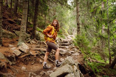 Yürüyüş yapan kadın, bahar yeşili ormanda yürüyüş yapan bir sırt çantasıyla yürüyor. Seyahat, doğa, aktif yaşam tarzı