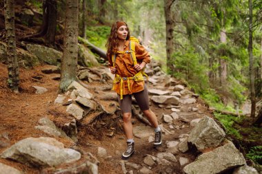 Yürüyüş yapan kadın, bahar yeşili ormanda yürüyüş yapan bir sırt çantasıyla yürüyor. Seyahat, doğa, aktif yaşam tarzı