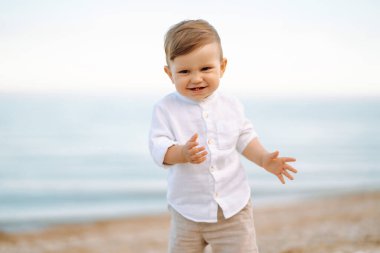 Küçük çocuk yazın gün batımında sahilde yürür. Mutluluk, sevinç, tatil, plaj, yaz konsepti.