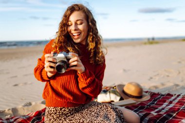 Genç kadın gezgin, doğanın fotoğraflarını retro kamerayla çekiyor. Piknik, rahatla, hafta sonu.