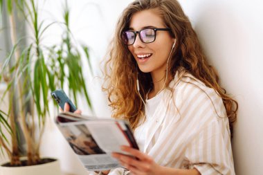 Evde cep telefonu kullanan gülümseyen bir kadın. Bloglama, serbest çalışma, çevrimiçi kurs, uzaktan çalışma, internet konsepti.