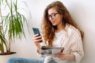 Evde cep telefonu kullanan gülümseyen bir kadın. Bloglama, serbest çalışma, çevrimiçi kurs, uzaktan çalışma, internet konsepti.