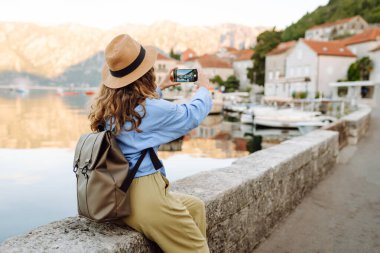 Güzel bir bayan turist sokaklarda yürüyor ve çekimlerin fotoğrafını çekiyor. Yaşam tarzı, seyahat, dinlenme, hafta sonu, aktif yaşam.