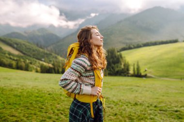 Sırt çantalı genç kadın doğa vadisine, dağlara ve sakin gündoğumuna bakıyor. Seyahat, doğa konsepti..