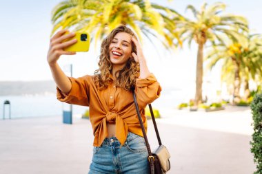 Bir turist sokakta yürürken akıllı telefon kamerasıyla selfie çeker. Olumlu anlar kavramı, eğlence.