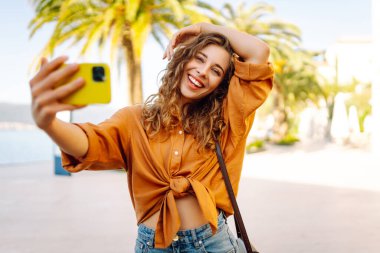 Bir turist sokakta yürürken akıllı telefon kamerasıyla selfie çeker. Olumlu anlar kavramı, eğlence.