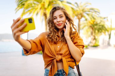 Bir turist sokakta yürürken akıllı telefon kamerasıyla selfie çeker. Olumlu anlar kavramı, eğlence.