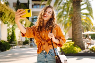 Bir turist sokakta yürürken akıllı telefon kamerasıyla selfie çeker. Olumlu anlar kavramı, eğlence.