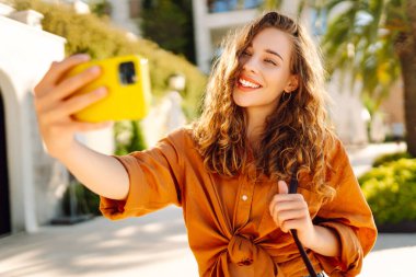Bir turist sokakta yürürken akıllı telefon kamerasıyla selfie çeker. Olumlu anlar kavramı, eğlence.
