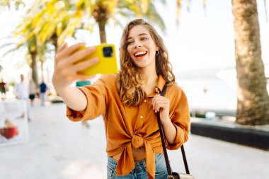 Bir turist sokakta yürürken akıllı telefon kamerasıyla selfie çeker. Olumlu anlar kavramı, eğlence.