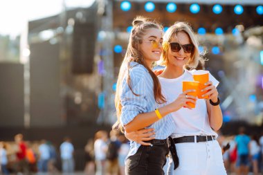 Plaj partisi. Müzik festivalinde bira içen iki genç kadın. Yaz tatili, tatil konsepti.