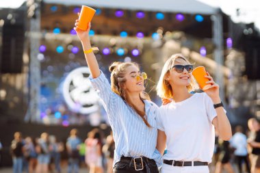 Plaj partisi. Müzik festivalinde bira içen iki genç kadın. Yaz tatili, tatil konsepti.