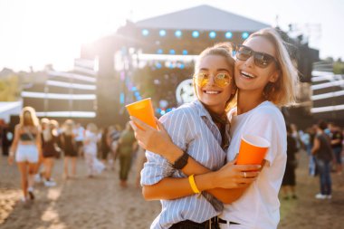Plaj partisi. Müzik festivalinde bira içen iki genç kadın. Yaz tatili, tatil konsepti.