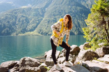 Mutlu turist kadın güneşli havada dağ gölü manzarasının tadını çıkarıyor. Görkemli dağların manzarası. Etkin yaşam biçimi.