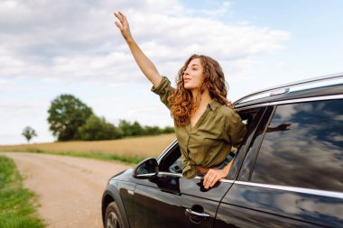 Yaz tatili seyahatinde araba camından sarkan mutlu kadın. Yaz gezisi. Doğa, ulaşım, aktif yaşam.