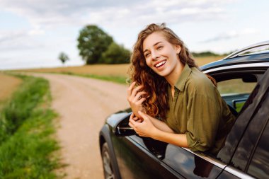 Yaz tatili seyahatinde araba camından sarkan mutlu kadın. Yaz gezisi. Doğa, ulaşım, aktif yaşam.
