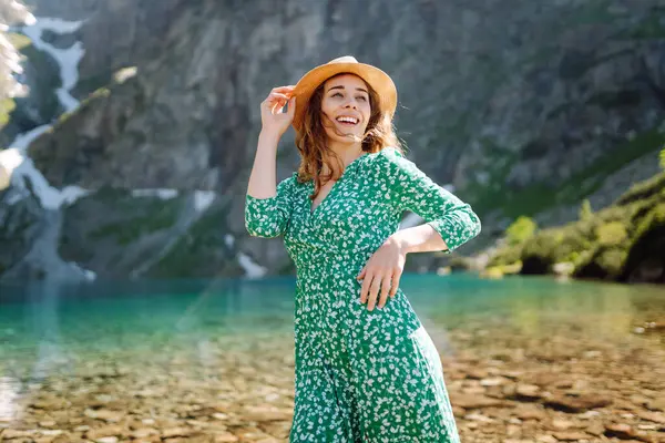 Yazlık elbiseli güzel kadın güneşli havada dağ gölü manzarasının tadını çıkarıyor. Görkemli dağların manzarası. Etkin yaşam biçimi.