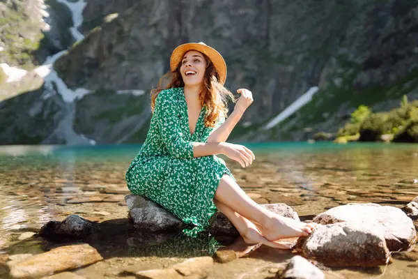 드레스에 여자는 날씨에 호수의 전망을 즐긴다 장엄한 산맥의 활동적인 라이프스타일 스톡 사진