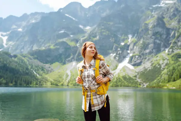 ハッピーな観光客の女性は 晴れた天気で山の湖の景色を楽しんでいます 壮大な山々の風景 アクティブライフスタイル ストック画像