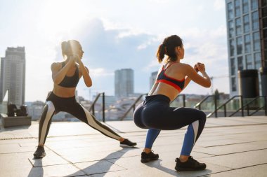 İki kadın birlikte dışarıda spor yapıyorlar. Sabah yoğun bir antrenmandan önce kaslarını ısıtıyorum. Spor, aktif yaşam, spor eğitimi, sağlıklı yaşam tarzı..