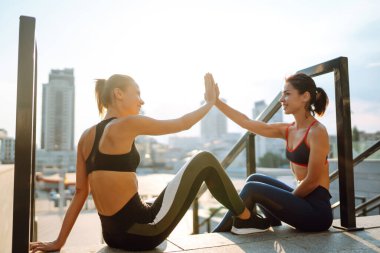 İki kadın birlikte dışarıda spor yapıyorlar. Sabah yoğun bir antrenmandan önce kaslarını ısıtıyorum. Spor, aktif yaşam, spor eğitimi, sağlıklı yaşam tarzı..