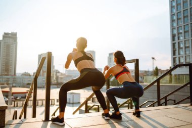 İki kadın birlikte dışarıda spor yapıyorlar. Sabah yoğun bir antrenmandan önce kaslarını ısıtıyorum. Spor, aktif yaşam, spor eğitimi, sağlıklı yaşam tarzı..