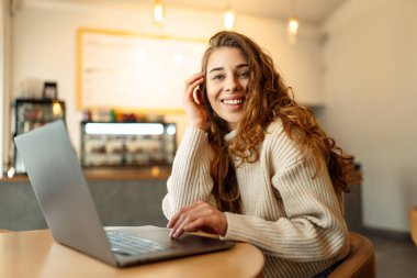 Şık bir bayan menajer, rahat bir kafede otururken dizüstü bilgisayarda çalışan serbest çalışan biri. Eğitim ve iş kavramı. İnternetten alışveriş.