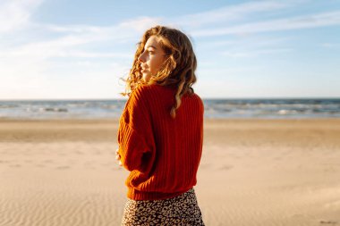 Gün batımında kumsalda yürüyen güzel bir kadın. Seyahat, hafta sonu, rahatlama ve yaşam tarzı konsepti.
