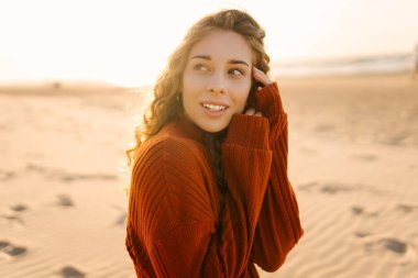 Gün batımında kumsalda yürüyen güzel bir kadın. Seyahat, hafta sonu, rahatlama ve yaşam tarzı konsepti.