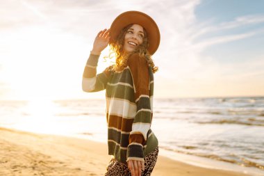 Gün batımında kumsalda yürüyen güzel bir kadın. Seyahat, hafta sonu, rahatlama ve yaşam tarzı konsepti.