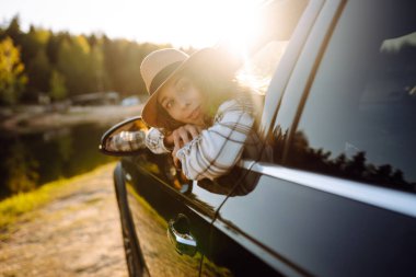 Yaz gezisinde arabasının camından sarkan rahat bir kadın. Yaşam tarzı, seyahat, turizm, doğa, aktif yaşam.