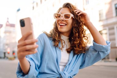 Neşeli bayan turist cep telefonunun ön kamerasıyla selfie çekiyor. Yaşam tarzı, seyahat, turizm, aktif yaşam.