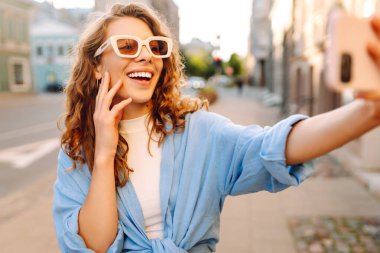 Neşeli bayan turist cep telefonunun ön kamerasıyla selfie çekiyor. Yaşam tarzı, seyahat, turizm, aktif yaşam.