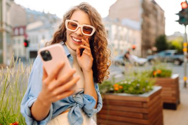Neşeli bayan turist cep telefonunun ön kamerasıyla selfie çekiyor. Yaşam tarzı, seyahat, turizm, aktif yaşam.