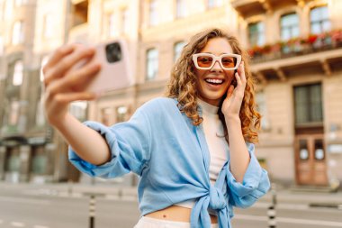 Neşeli bayan turist cep telefonunun ön kamerasıyla selfie çekiyor. Yaşam tarzı, seyahat, turizm, aktif yaşam.